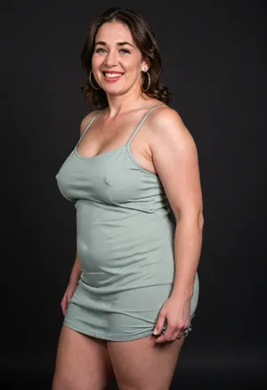 3/4 side view, Curvy gilf, looking at viewer, eye contact, portrait photo a ssbbw mature 60 year old woman, wearing a v-neck sleeveless spaghetti strap light green maxidress, hourglass figure, wide, huge hips, large waist, narrow waist, thick, thighs, saddlebags, round face, chubby cheeks, wrinkles, flushed cheeks, double chin, big eyes, long hair, brunette hair with highlights, medium hair, big smile, mouth open, lips parted, big lips, teeth showing, perfect teeth, joyful smile, (solid blank black background), pokies, hoop earrings, (wrinkles), sagging, breasts, apart, hard nipples, huge ass