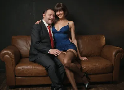 (ultra realistic, ultra detailed, best quality, realistic style, soft shadows, soft light, cinematic), (black room, brown leather sofa), man and woman on sofa, man hugs a woman, man grabs a woman, skinny 40 yo old russian brunette mature wife, (dark medium-length bob hair with bangs), (thin narrow triangular face, narrow long nose, feint small amount of freckles across nose, thin narrow lips, dark grey eyes, caucasian face type, no makeup), (short petite skinny body, (skinny:1.3)), short skinny legs, wide thigh gap, skinny flat ass, skinny hips, slightly tanned skin, no tattoos, short tight dark blue dress, (brown stockings:1.3), black high-heeled shoes, face expressions, laughing, (realistic faces:1.3), (perfect face:1.3), (perfect eyes:1.3), perfect hands, realistic detailed eyes, (realistic mature skin texture:1.3), (fat man, 50 years old wearing in black suit, blue shirt, red tie, shaved face, short dark hair)