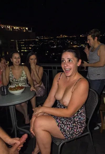 Realistic photography, Amateur picture of a regular mature wife on a family gathering, picture taken from far away, (she is not aware:1.1), (she is wearing a random dress:1.1), (dress:1.1), she has a shorty petite body, she is 40 years old, (extremely detailed realistic skin texture), skin imperfections, pimples, flappy, saggy, flaccid, cellulite, she is classy sat down on a chair by the table at apartment balcony, she is shy, she is ashamed, she is embarrassed, she has a beautiful mature face, (she seems very surprised, worried, scared, giggling), (people nearby, people in the back, group of people, crowd, busy place, crowded place), nighttime, dark night off, she is wearing some basic jewelry. Food. Drinks. Spontaneous picture vibe. She is a Well behaved lady. Tiny breasts. Sagging breasts. Nipples, she is wearing a very soft and natural makeup, soft tan lines, gently sun kissed. There is a male silhouette nearby, (She is holding a huge black penis), She is flaunting the black cock she is holding, cock worship, (dark eyes)